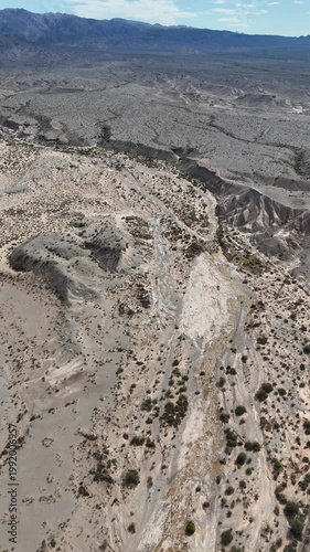 Dry riverbed with mineral formations and cracked mud in arid landscape under blue sky