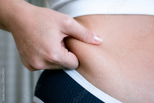 Woman weight check. Female examining torso fat indoors. Self car