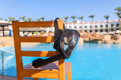A black mask with a snorkel for scuba diving hangs on a lifeguard chair.