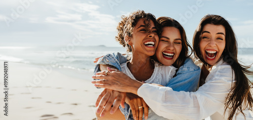 Foto Three friends laughing and hugging together on a bright sunny beach