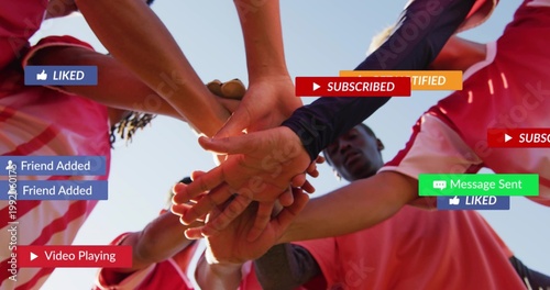 Reaching eight players in red jerseys stacking hands against sky with dark sleeve and notifications
