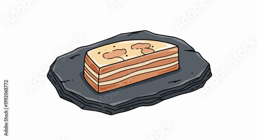 A layered, rectangular cake with light brown and cream layers, topped with lighter brown splatters and dark dots, sits on a dark, flat stone