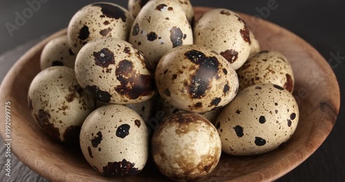Quail eggs in a wooden bowl, close-up footage on a rotating table.
