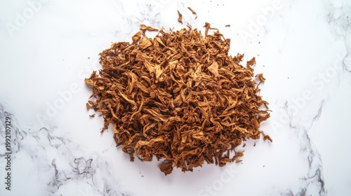 Loose golden tobacco flakes spread on a white surface