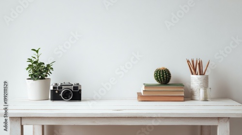 Minimalist workspace with vintage camera and houseplants on white desk