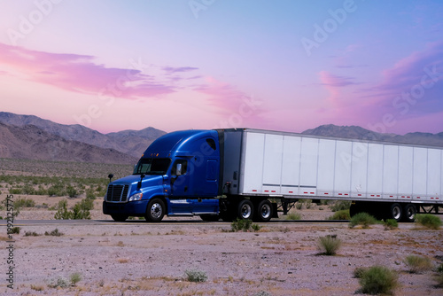 Truck driving on highway through nature and mountains. Commercial vehicle transport for logistics and shipping.