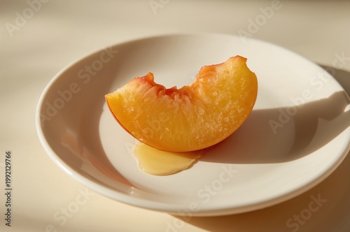Ripe peach slice resting on white plate in warm gentle morning light glow
