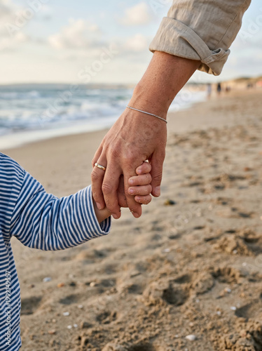 Mother and child walking hand in hand on the beach