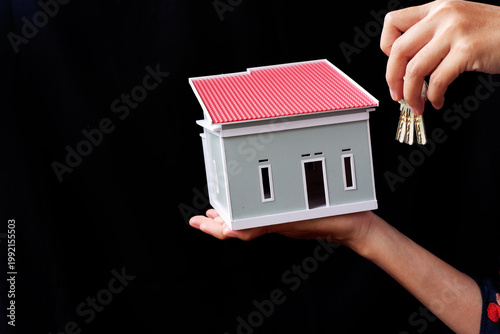 Hold the keys to the house and the miniature house. Success in buying your dream home.
