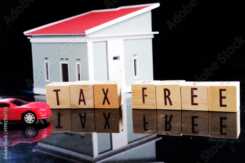 Miniature cars and miniature houses, with the words TAX FREE written on a dark background. Tax exemption with certain conditions.
