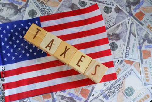 The word TAXES with a US flag and dollar background. Implementation of American state taxes
