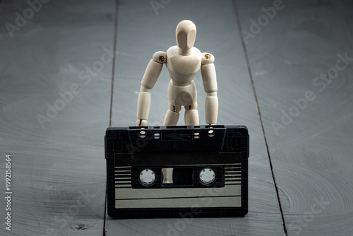 Artist mannequin beside retro cassette tape, analog memory and stillness theme