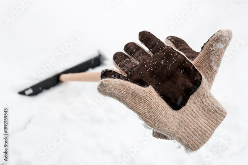 knitted gloves were left after work on the handle of a snow shovel