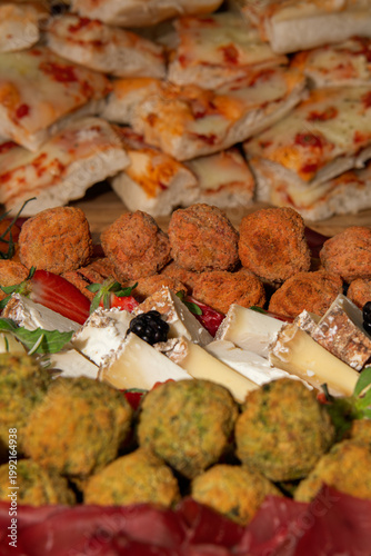 Close-up of a festive appetizer platter with pizza slices, fried bites, cheese and fresh berries, arranged for a party buffet with a warm, inviting mood.