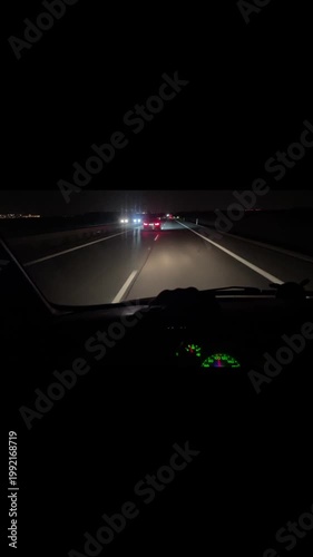 Night highway drive from dashboard, car headlights cutting darkness, taillights ahead, empty lanes and guardrail, tense motion and speed in long exposure vertical stock video