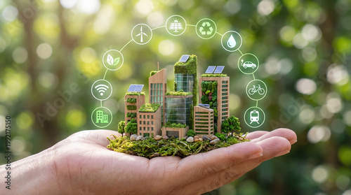Hand holding wooden miniature model of sustainable smart city with vertical gardens and renewable energy icons, green urban development and future eco technology concept