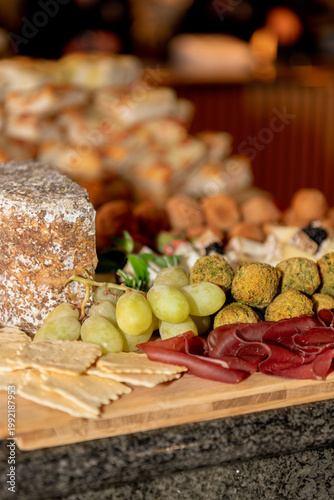 Gourmet charcuterie board with artisanal cheese, grapes, cured meat, crackers, and savory bites, warmly lit for a cozy, elegant dining atmosphere.