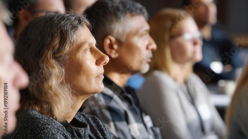 Group of people sitting in a lecture hall, attentively listening to a presentation. the focus of the image is on a woman's face, who appears to be deep in thought.