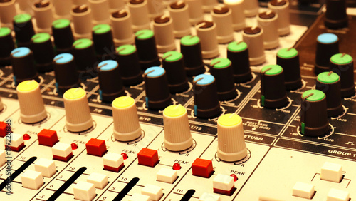 Colorful knobs and sliders dominate a professional audio mixing console