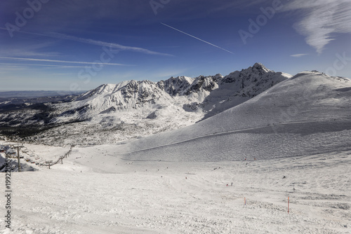 Mountains and slopes covered in snow with skiers enjoying the winter day. Kasprowy Wierch, Zakopane, Poland