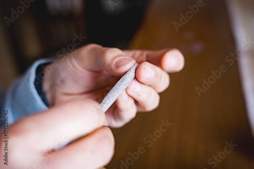 close up of hands of young woman rolling cigarette paper with tobacco , concept of smoking addiction