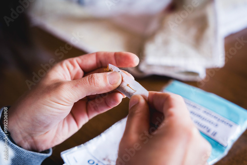 close up of hands of young woman rolling cigarette paper with tobacco , concept of smoking addiction