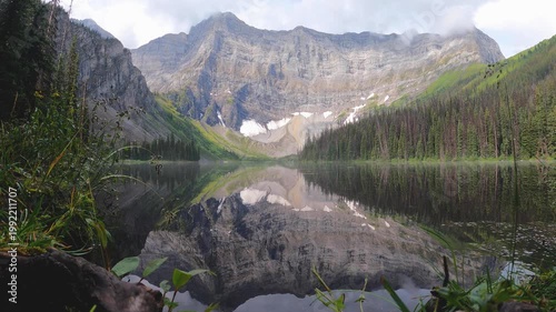 stunning stunning alpine lake located in Kananaskis Country, Alberta landscape featuring a serene surrounded by lush green slopes, rocky peaks, clear water. Perfect for showcasing adventure, hiking.