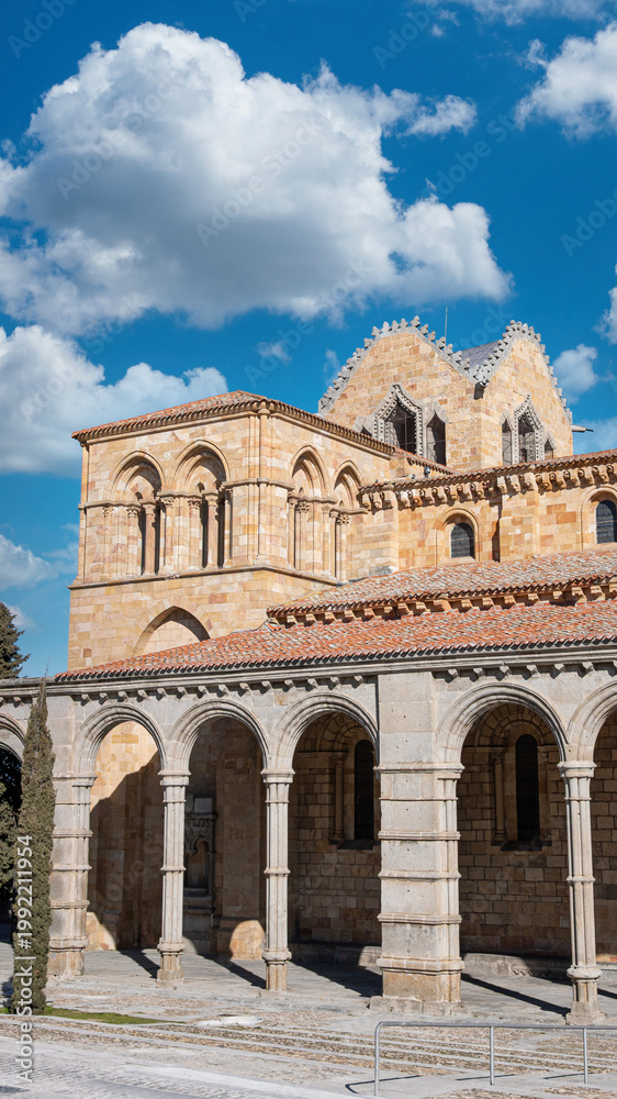 Fototapeta premium Fotografía vertical campanario y arcada de la basílica de los hermanos santos Vicente, Sabina y Cristeta de estilo románico en Avila, España. Con cielo editado
