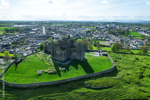 Aerial drone view of the Rock of Cashel, a historic medieval cathedral and fortress rising above the Irish countryside.