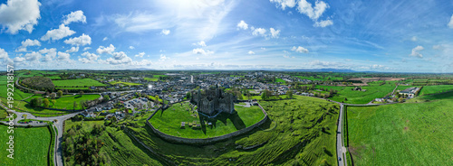 Aerial drone view of the Rock of Cashel, a historic medieval cathedral and fortress rising above the Irish countryside.