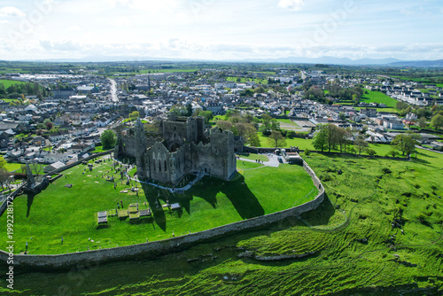 Aerial drone view of the Rock of Cashel, a historic medieval cathedral and fortress rising above the Irish countryside.