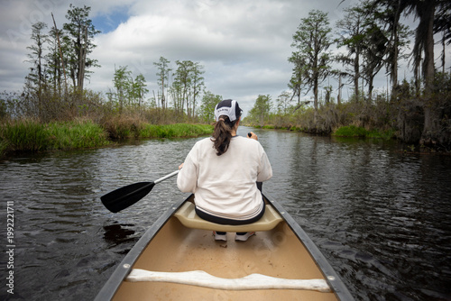 A woman paddles a canoe through the Okefenokee Swamp of Southern Georgia, USA.