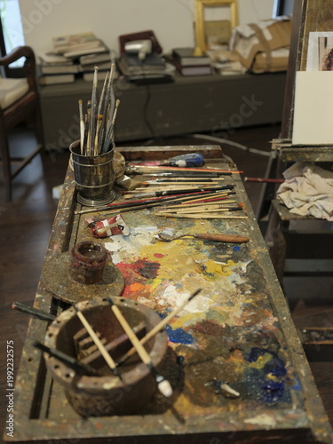 Painter’s workspace with brushes and colorful palette in art studio