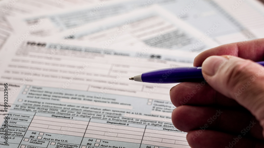 Obraz premium Hand holding pen preparing 1040 income tax form