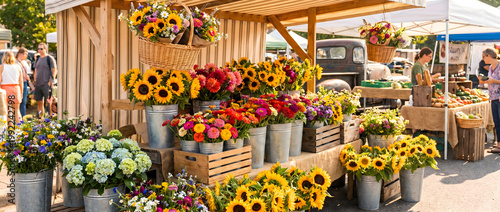 Outdoor farmers market stall displaying sunflowers and hydrangeas in metal buckets and wooden crates