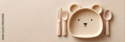 Obraz  z motywem Baby feeding accessories. First safe bear shaped plate, fork, spoon, bib. Silicone tableware, cutlery set on beige neutral background. Kids dishware concept. Serving child food. Solid color backdrop.