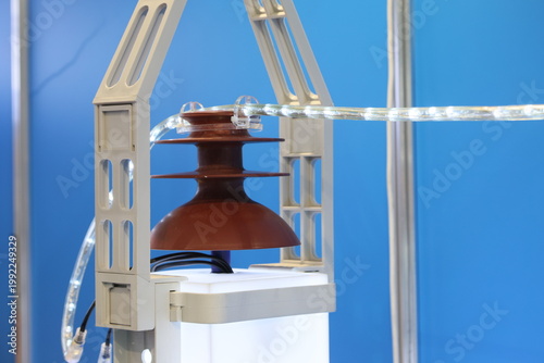 Brown ceramic electrical insulator with LED wire on blue background.