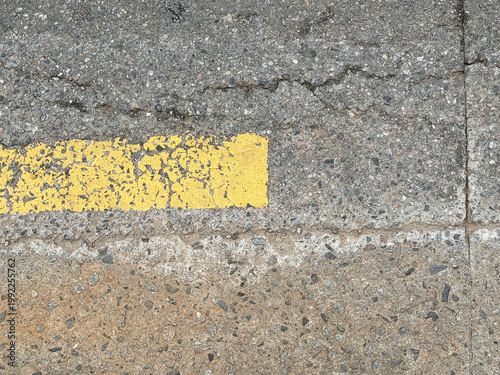 Cracked Asphalt with Yellow Line - Realistic close-up photo of gray concrete pavement texture with worn yellow road marking. Ideal for urban backgrounds, 3D rendering, architectural visualization, and