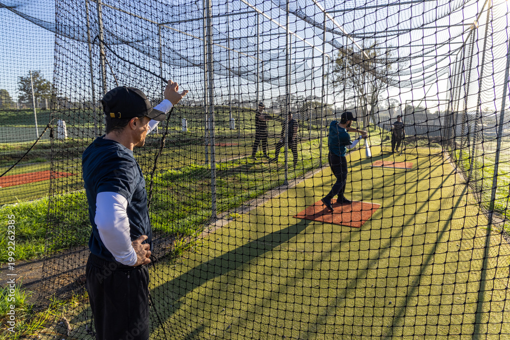 Fototapeta premium Coach signaling, batter swinging during baseball practice in cage, animated lines showing bat path