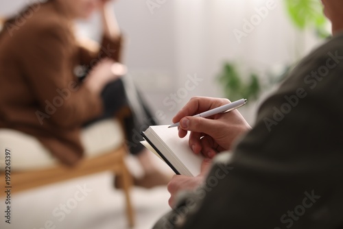Obraz na plátně Professional psychologist making notes during therapy session with patient indoo
