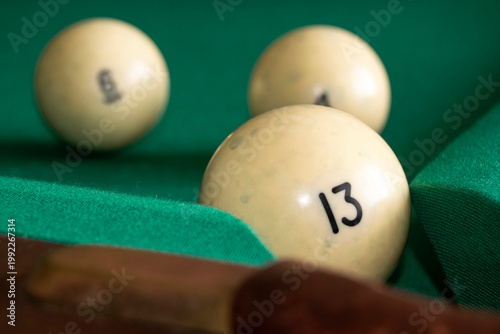 The billiard ball is on a green billiard table. Billiards is a popular sport. There is a number of thirteen on the billiard ball.