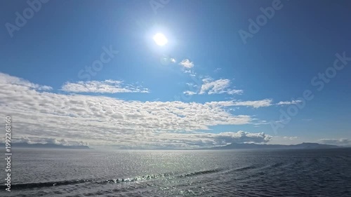 August 13, 2024 - Tracy Arm, USA - View of the calm waters in fjord. Clouds are reflecting off the water surface. The landscape shows distant mountains surrounded by clouds.