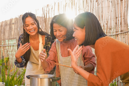 Happy asian mother cooking fresh thai soup with daughter's at house backyard - Mom day, family love and traditional food concept