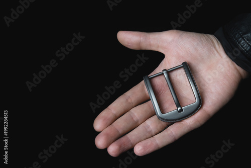 Elegant metal belt buckle showcased in palm, sophisticated dark setting, accessory focus
