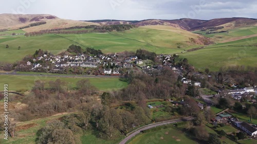 A peaceful Scottish village of Eddleston nestled among lush green fields and rolling hills in the rural Borders countryside