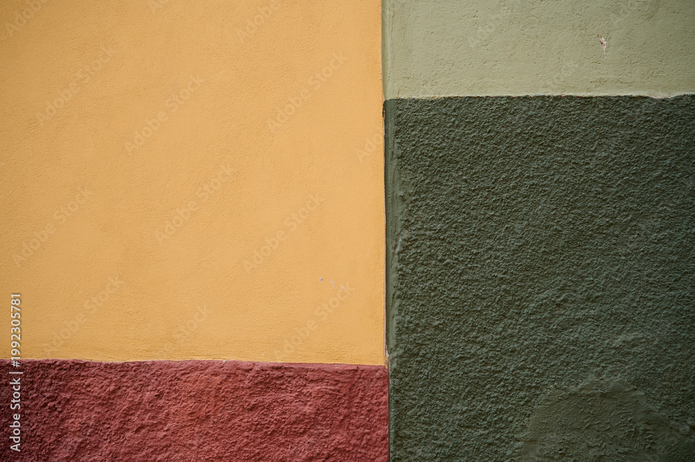 Fototapeta premium A colorful wall section in San Miguel de Allende, Guanajuato, Mexico, showcasing textured surfaces and vibrant painted areas with distinct regional architectural character.