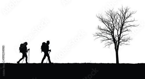 Two backpackers trekking across a field towards a bare tree silhouette in the bright white morning light
