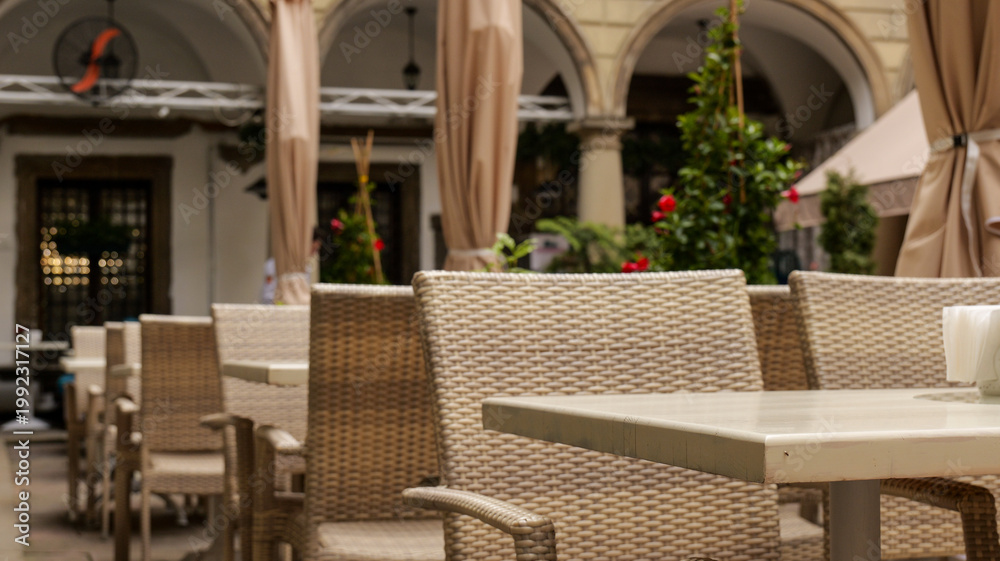Fototapeta premium Outdoor cafe seating with wicker chairs and tables under arches