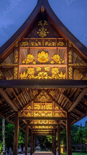 Traditional Thai Architectural Wood Pavilion With Ornate Golden Floral Carvings At Twilight Night Scene In Lush Tropical Garden Park Setting