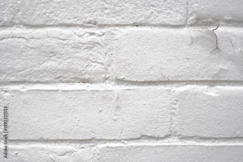 Bild auf Leinwand A close-up view of an old brick wall painted in white featuring cracks peeling p